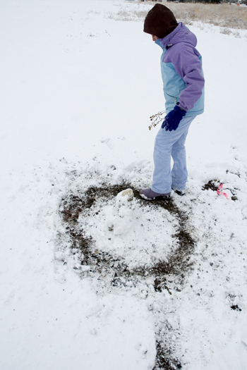 girl making circle in snow with her foot